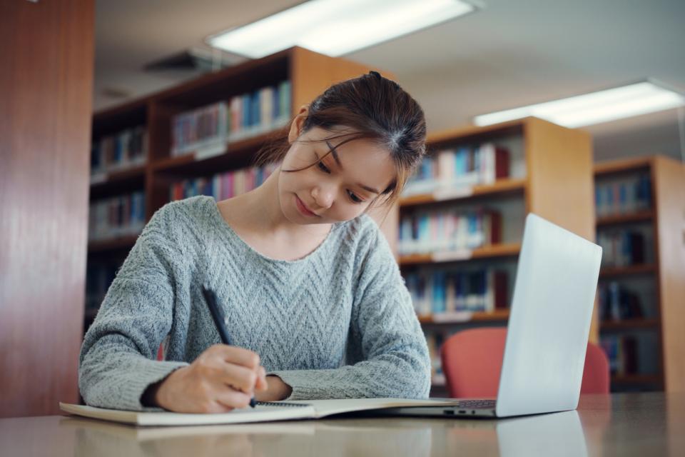 A university student taking notes by her laptop