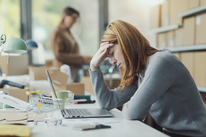 A young woman puts a hand to her head while working at an office