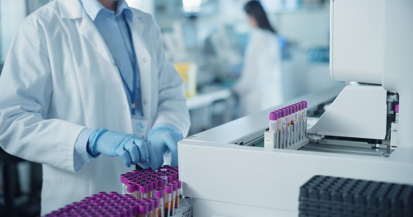 A white-coated figure handles test tubes