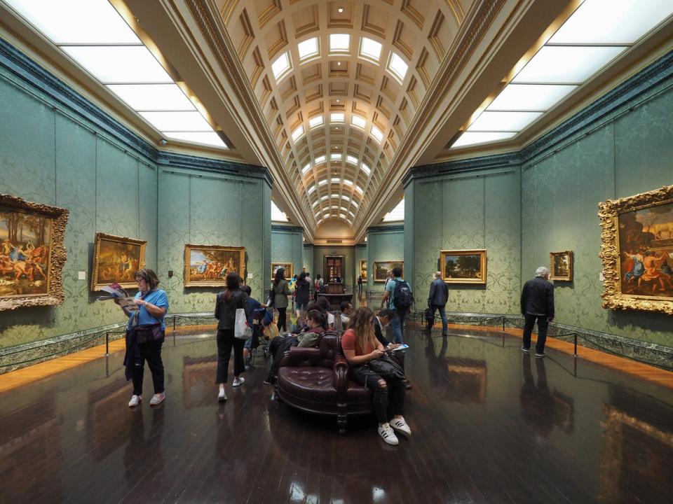 The interior of an art gallery with people walking around