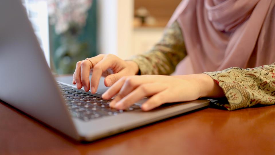 An unseen person at a laptop typing