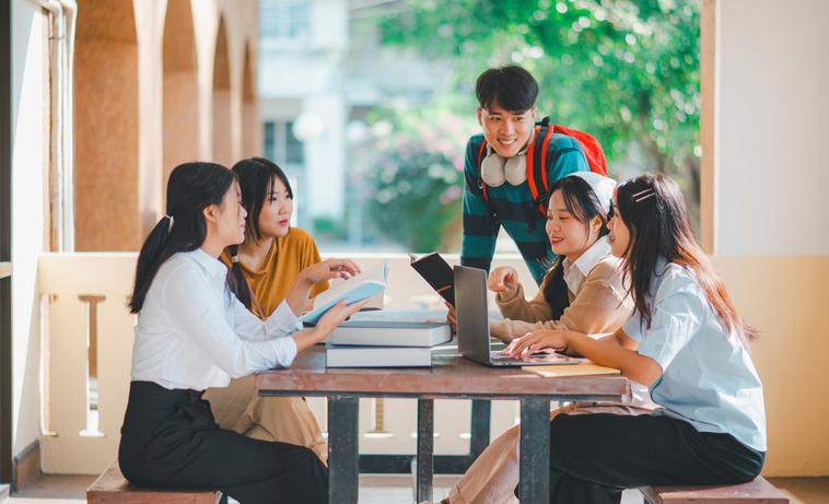 Students discuss their work round a table