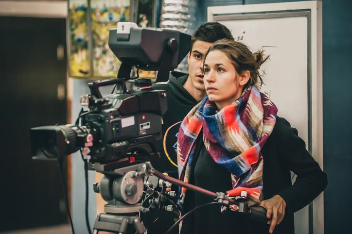 A young woman operates a camera