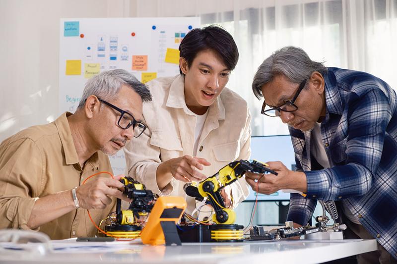 Three Asian men working on a robot