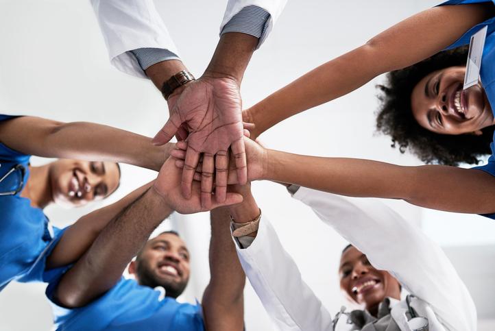 Doctors of colour clasp hands in a circle