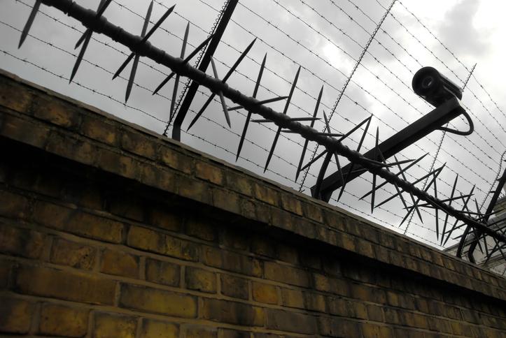 Barbed wire and a security camera on a brick wall