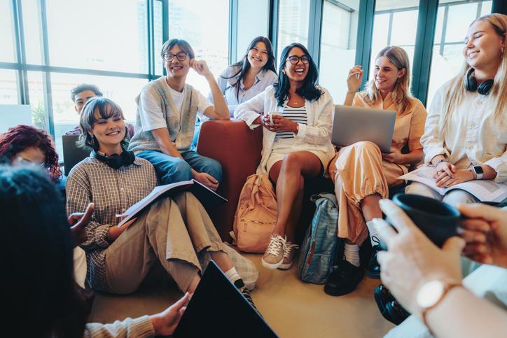 Students laugh together with a laptop