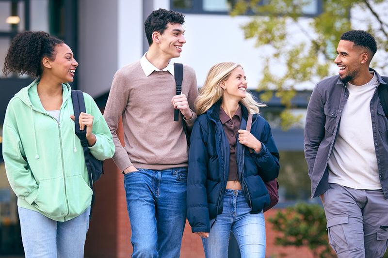 Group of four smiling college students walking
