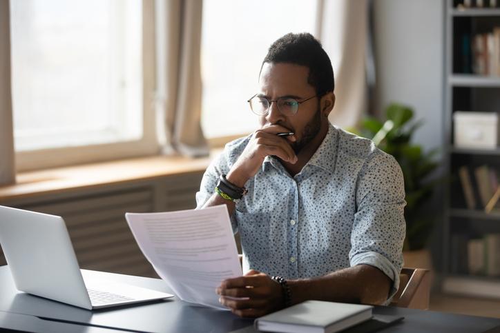 A man sitting at a laptop concentrates hard on a document