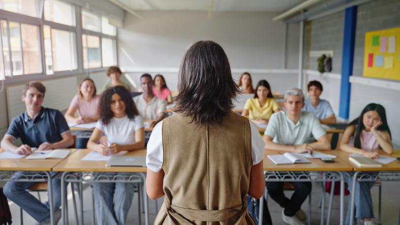 A university educator stands in front of a classroom