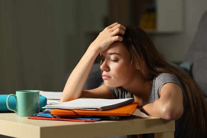 A student slumps over a pile of paperwork