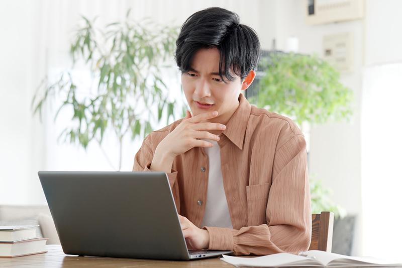 Male Asian student working at laptop