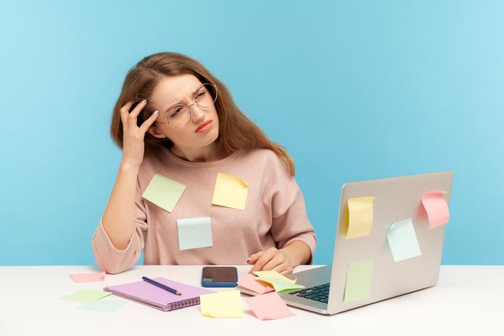 A student sits in front of a laptop, covered in Post-It notes