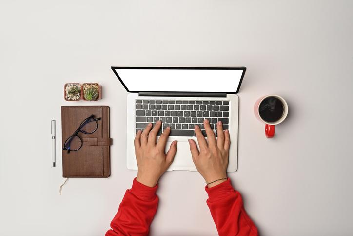 Hands type at a laptop, as seen from above