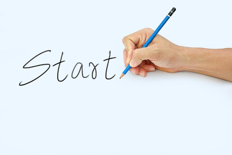 Start written on black page with hand holding a pencil
