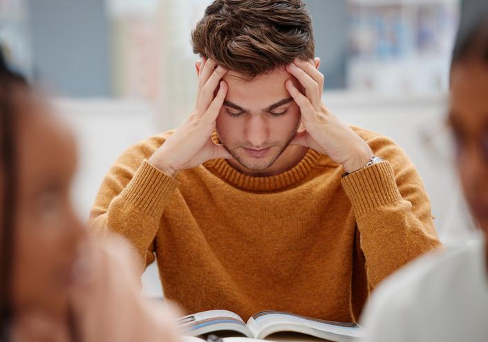 A student holds his head as he reads