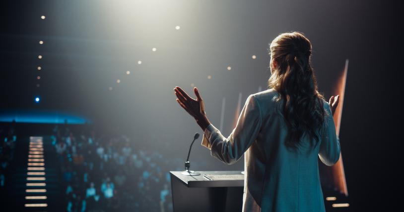 A woman speaks in front of an audience