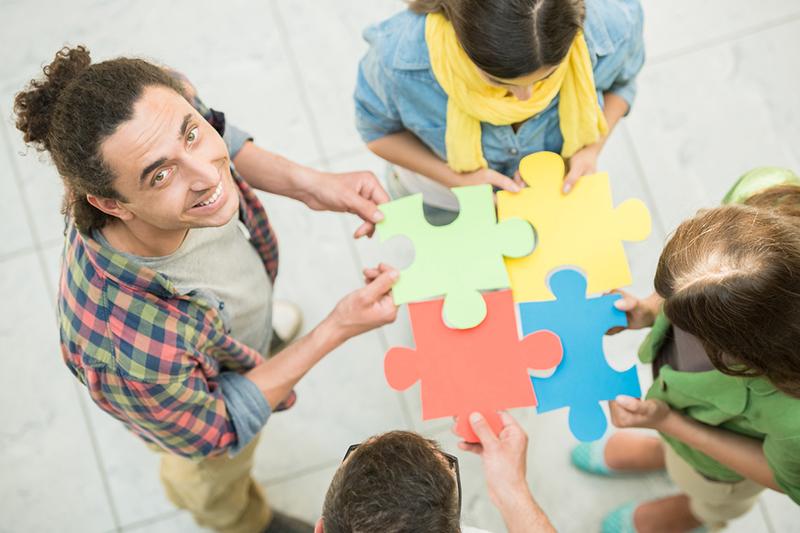 Group of young people holding jigsaw pieces, belonging concept