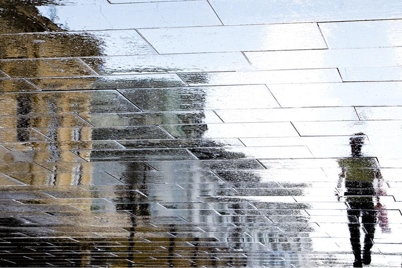 Distorted reflection of a man walking in the street