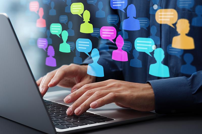 Man's hands over laptop keyboard with figures and speech bubbles