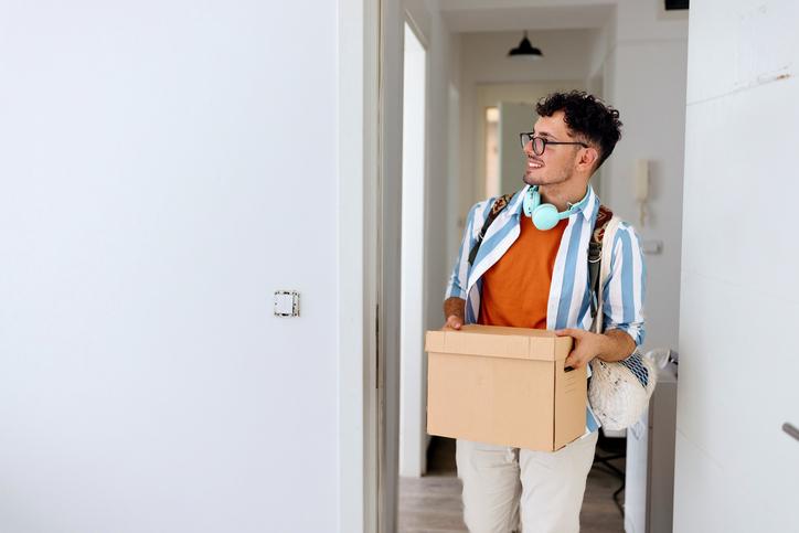 A new students arriving at his accommodation with a box of belongings