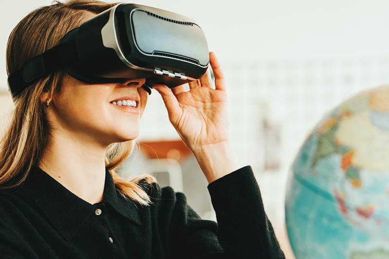Young woman wearing virtual reality headset with globe in background
