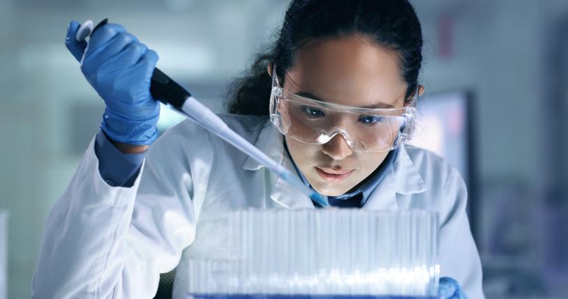 A close up of a researcher in a lab filling a test tube 