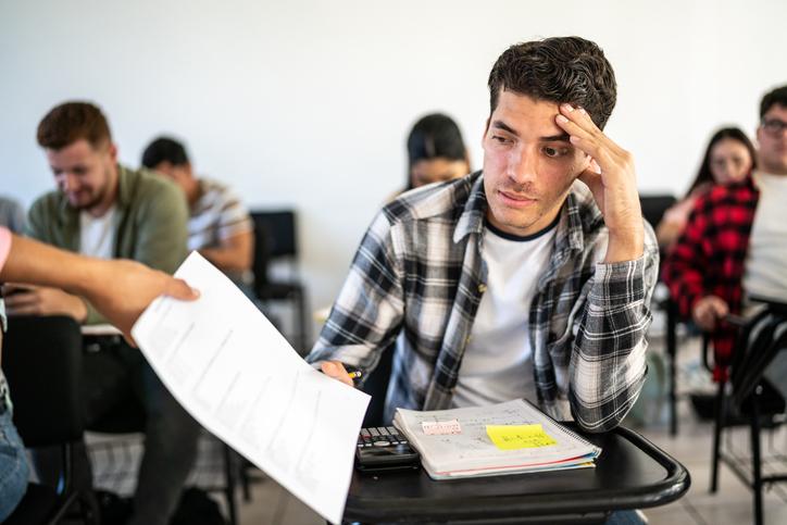 An unenthused student receives a test back in the classroom