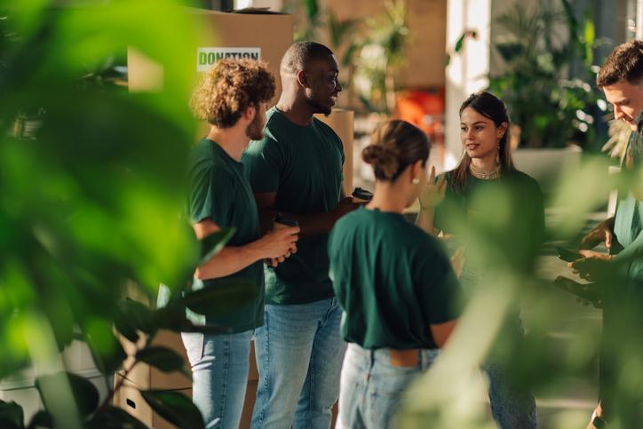 A group of students wearing green t shirts discussing a sustainability initiative