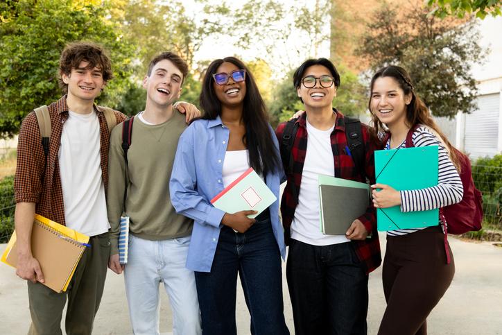 A group of smiling students standing outside on university campus grounds