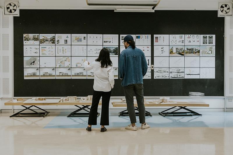 Architecture students inspecting plans on a board