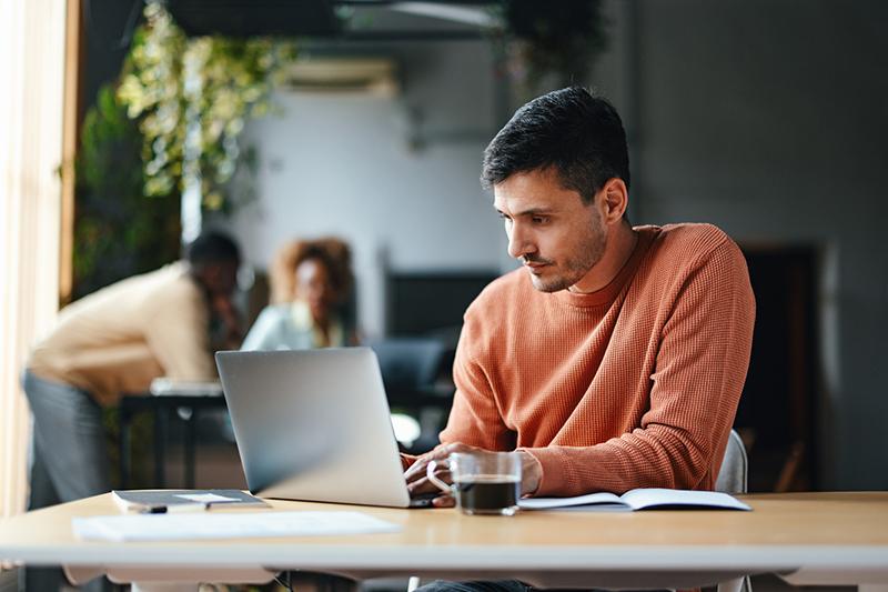 Caucasian male working at laptop in cafe