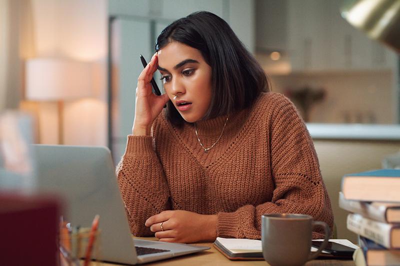 Young female student looking confused at laptop