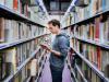 A man standing browsing papers in a university library