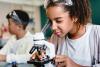 Young girl school pupil looking through a microscope