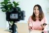 A young woman recording herself presenting on camera