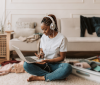 Student in her bedroom sitting on the floor on her laptop listening to music