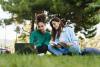 Two students sitting on the grass outside working at a laptop