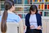 Female student support staff member taking notes as a student speaks to her