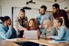 A group of students gather round a laptop