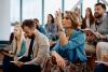 Engaged female student in lecture raising hand