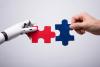 A robot and human hand put two jigsaw puzzle pieces together