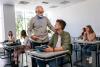 A lecturer speaking to a student at their desk