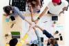 A group of students fist-bump over a table of work