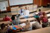 Students sitting at their desks in class while a teacher speaks