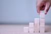 A hand places a wooden block atop three others
