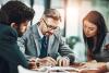 Three people looking at a page in a meeting