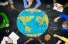 Top down view of people working on a table around an image of the globe