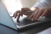 Hands typing on a laptop keyboard