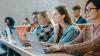 Students in a lecture hall typing on their laptops